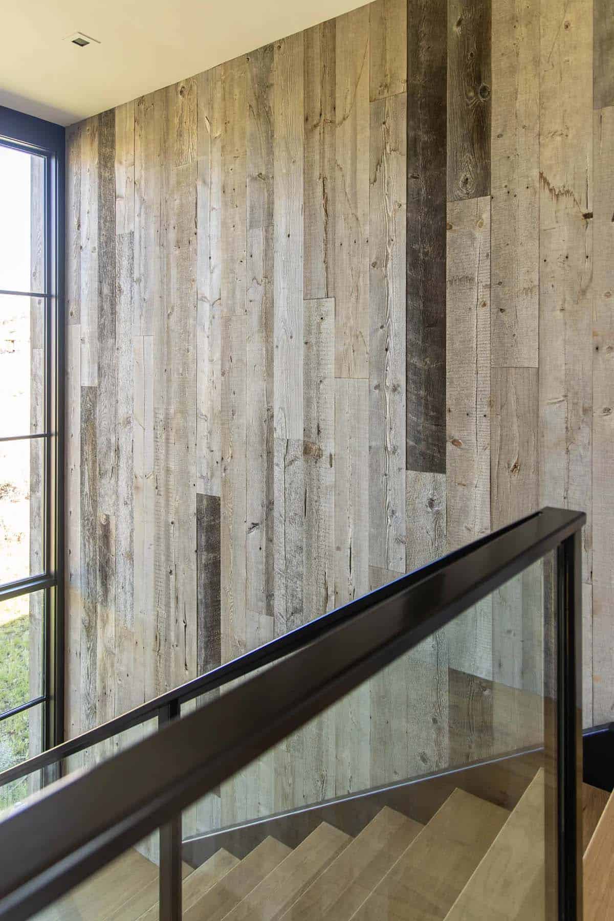 Close-up of reclaimed wood stairwell accent wall with black steel and glass railing