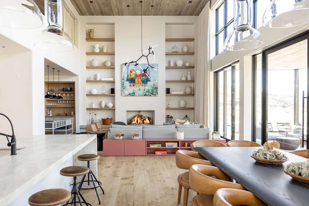Wide-angle great room view from kitchen showing fireplace wall, terracotta media console, bar niche, and dining area