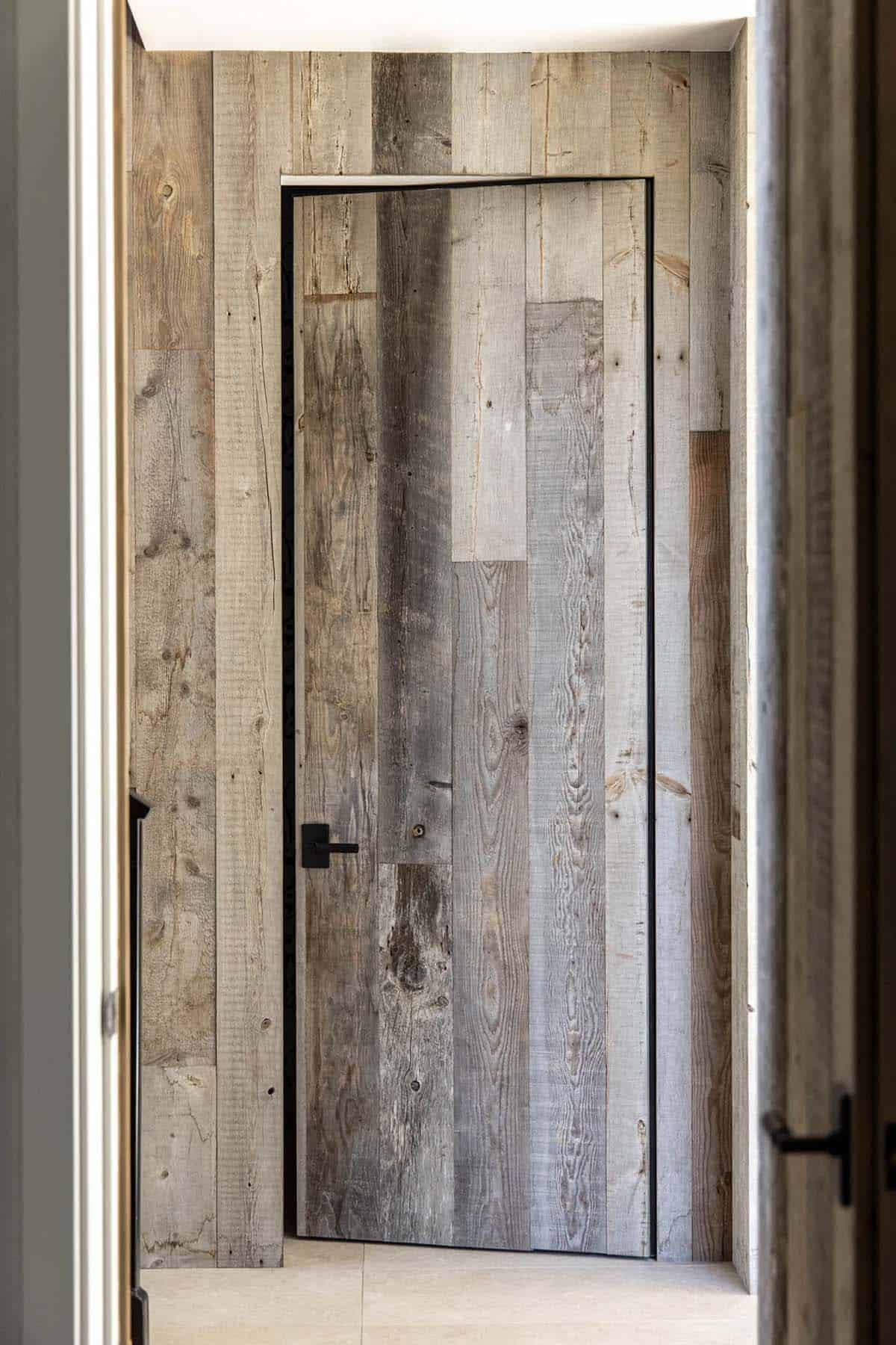Hallway with reclaimed wood accent wall and a reclaimed wood flush door with matte black handle