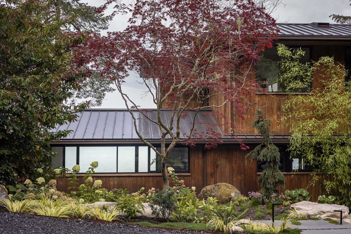 Cedar-clad exterior with standing-seam metal roof framed by Japanese maple and lush garden plantings