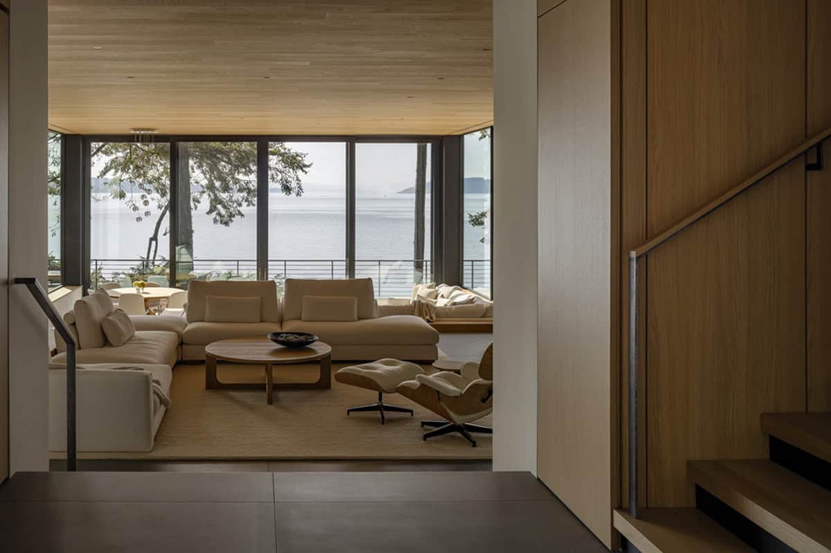 Entry hallway looking into sunlit living room with cream sectional sofa and panoramic water views