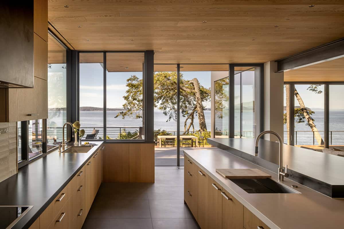 Kitchen with dual islands, light wood cabinets, and open corner windows framing water and tree views