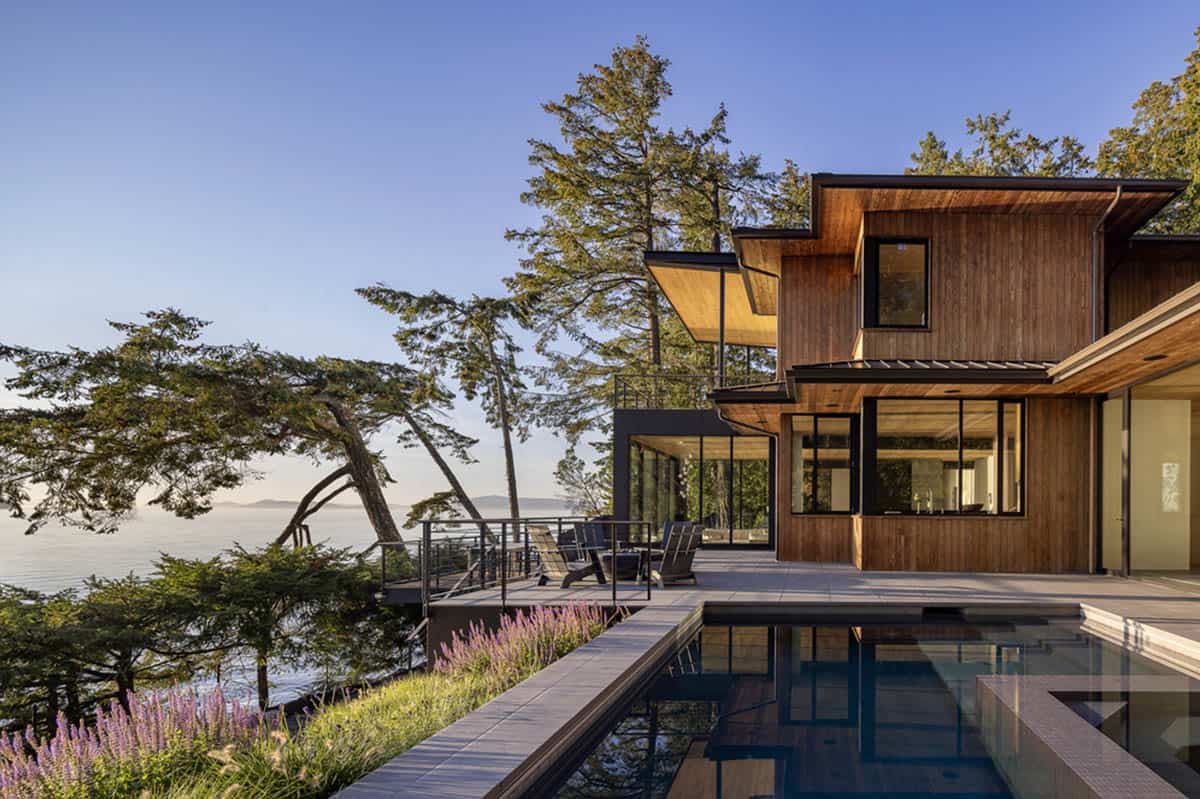 Exterior waterside view showing pool, lavender-lined terrace, and cedar-clad home at golden hour