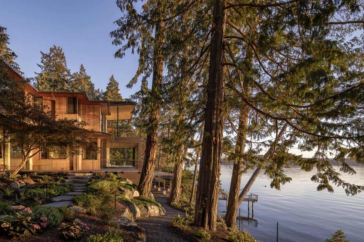 Golden hour view of cedar home through towering Pacific Northwest trees leading to private dock