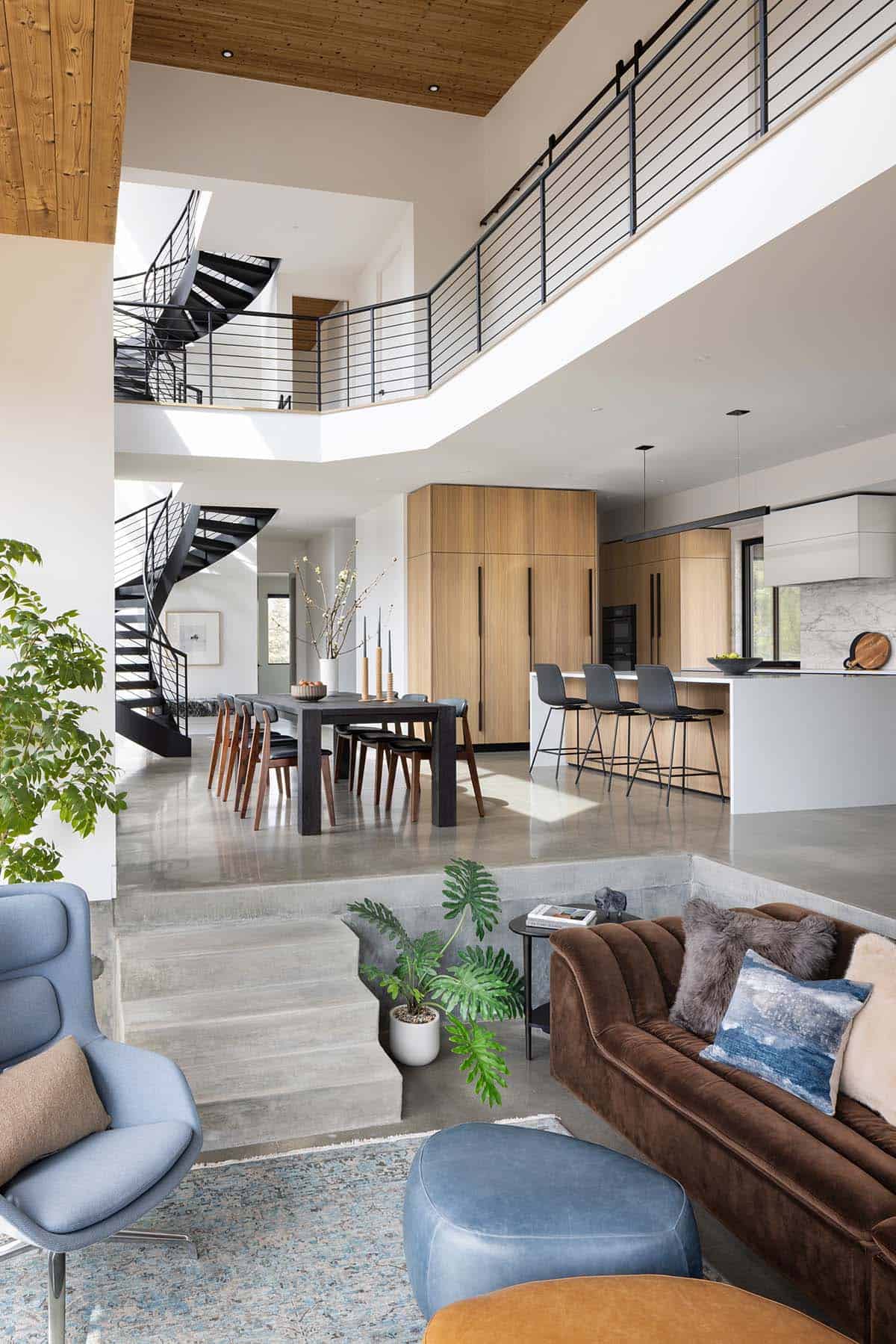 Open-plan living, dining, and kitchen with sunken living area, spiral staircase, and double-height ceilings
