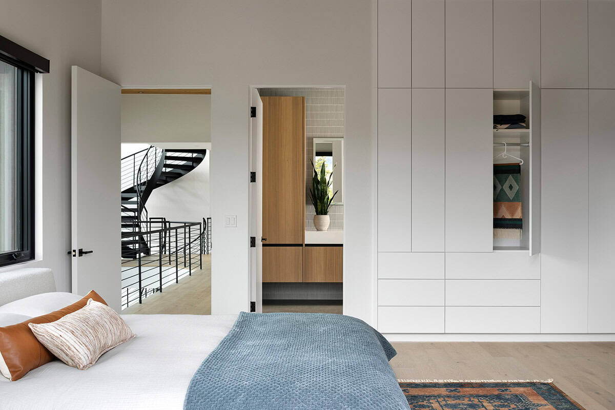 Guest bedroom with floor-to-ceiling built-in white cabinetry, blue coverlet, and views to spiral staircase and ensuite