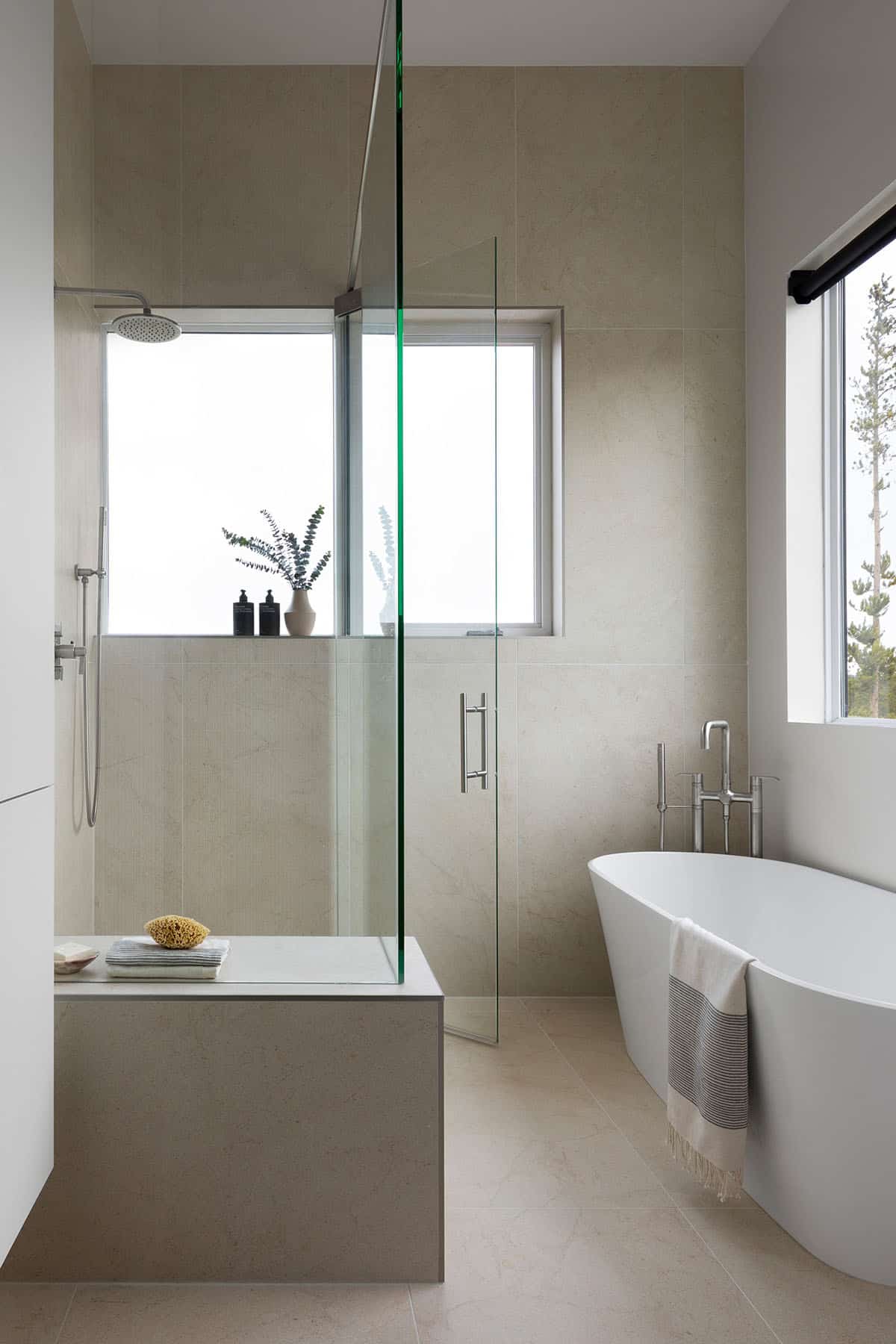 Primary bathroom with walk-in glass shower, freestanding soaking tub, and large format stone tile walls