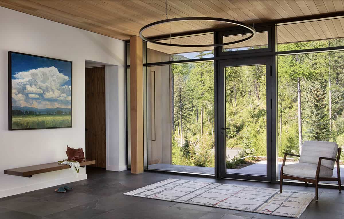 12:39 PMClaude responded: Montana cabin entryway with floor-to-ceiling windows framing a pine forest view, wood ceiling, and circular pendant light.Montana cabin entryway with floor-to-ceiling windows framing a pine forest view, wood ceiling, and circular pendant light
