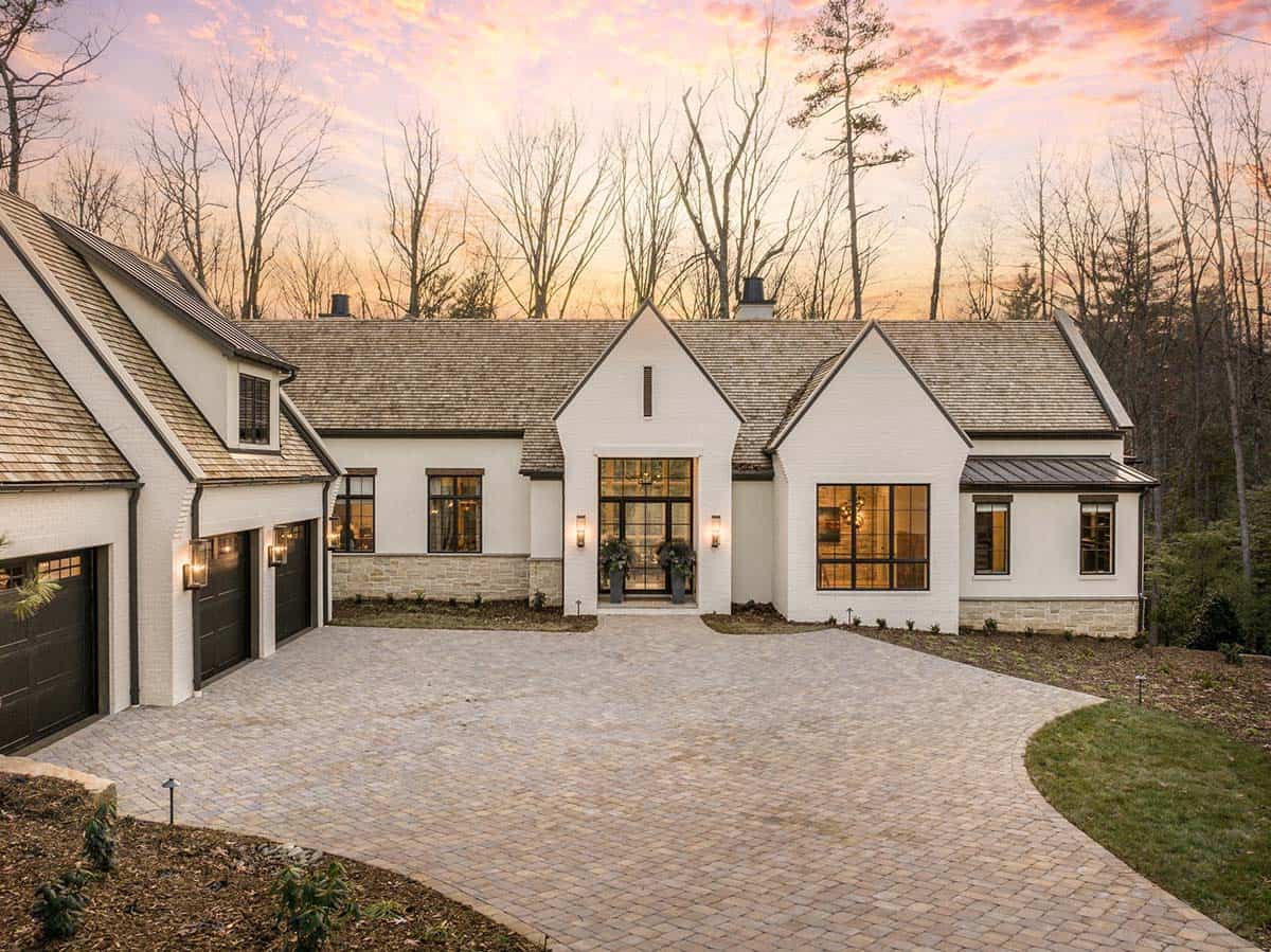 Front facade of white brick mountain home at sunset with black-framed entry doors