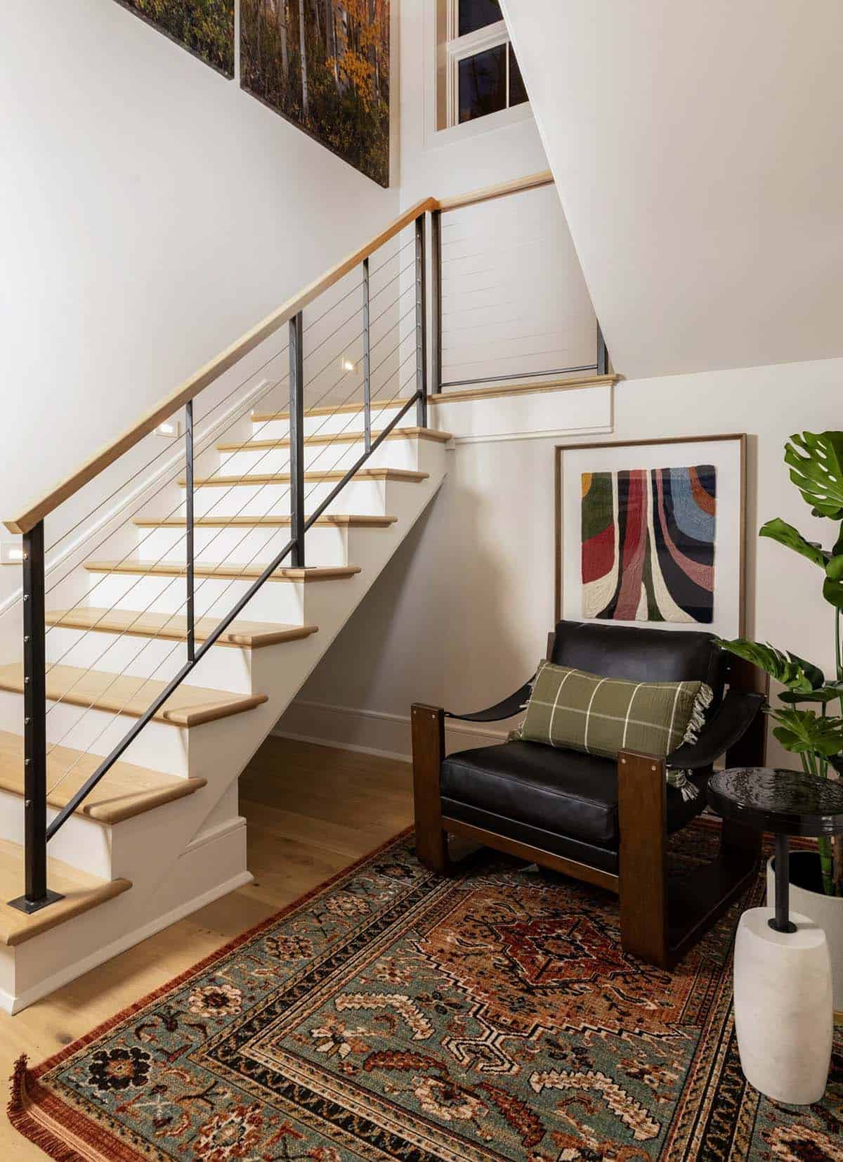 Staircase with cable railing, wood treads, and leather accent chair on patterned rug