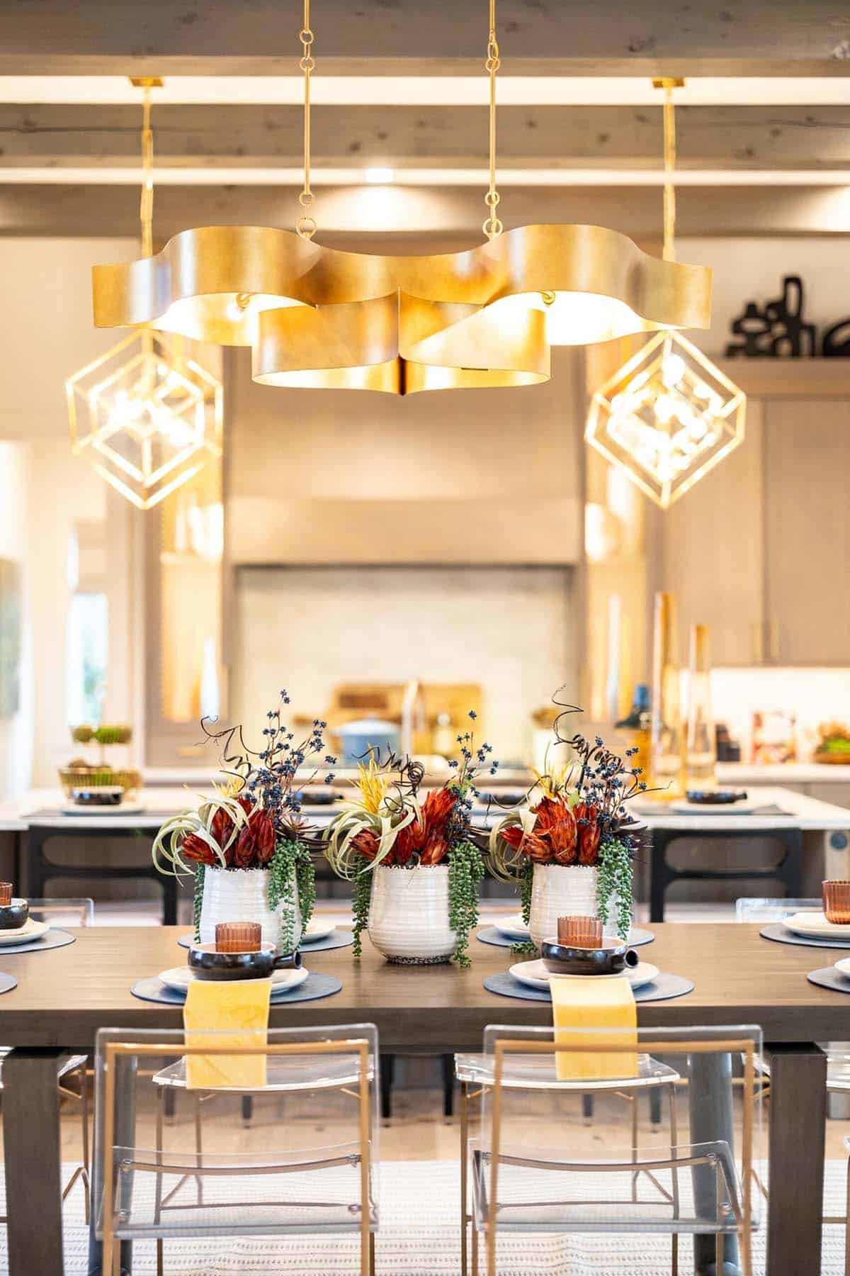Dining room close-up with sculptural gold chandelier and exotic floral centerpieces