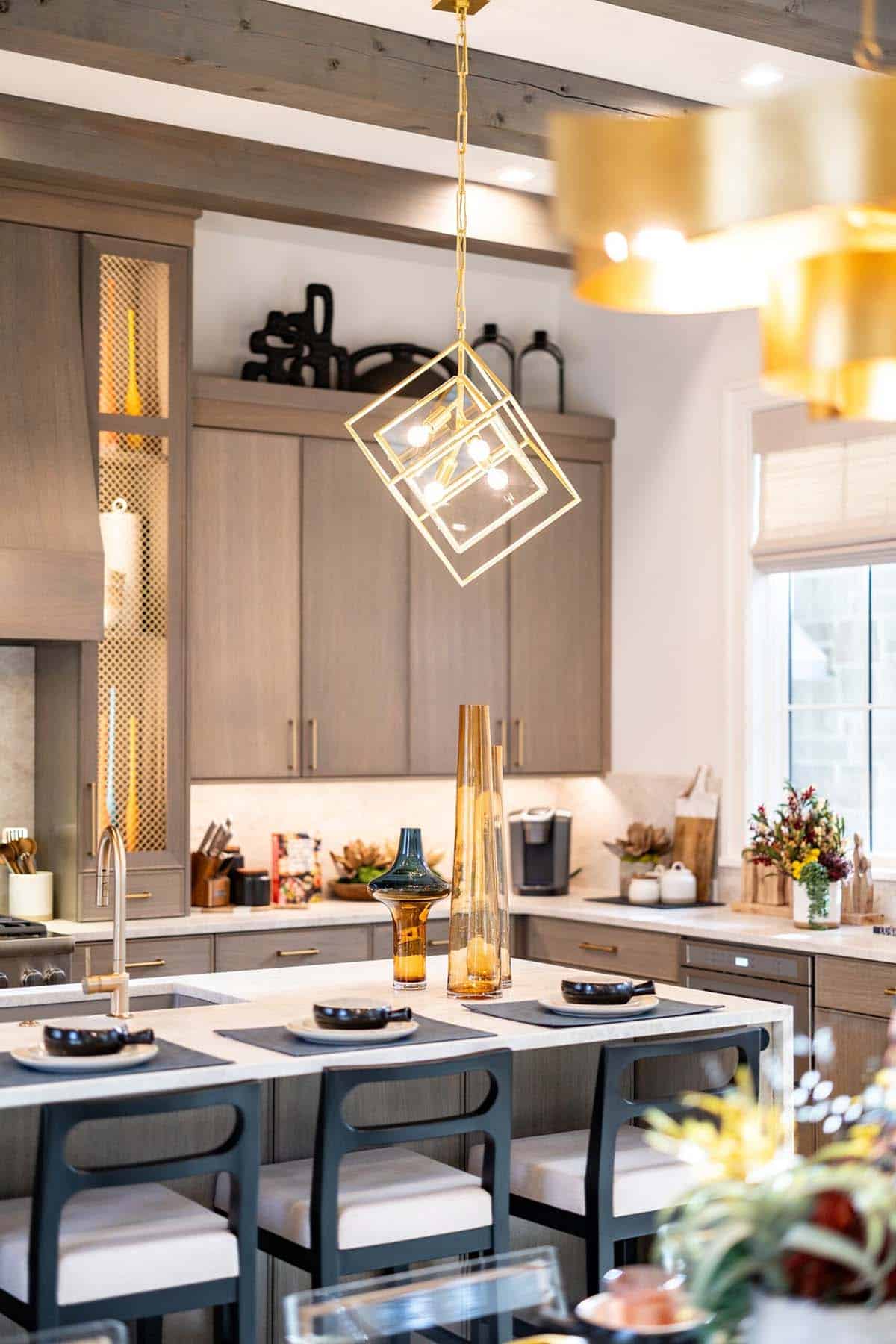 Kitchen island with gold geometric pendant light and taupe cabinetry