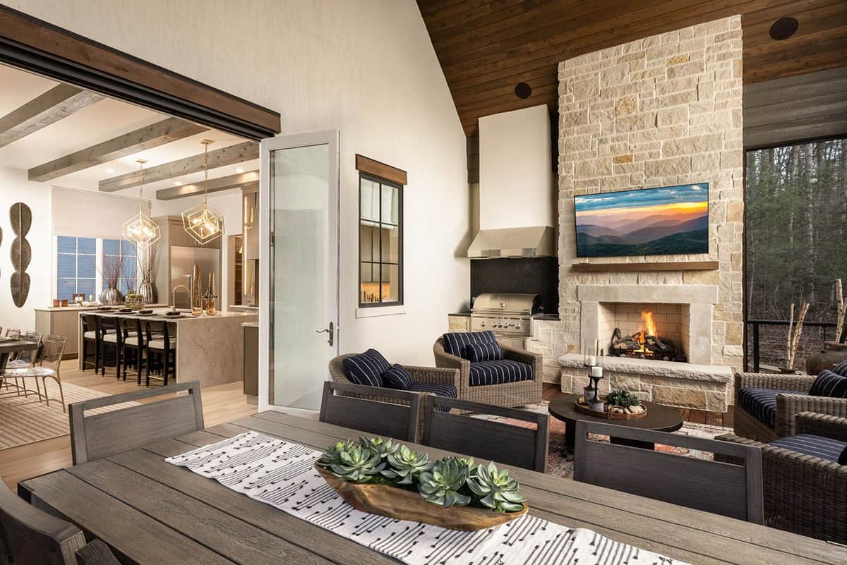 Screened porch with outdoor kitchen, stone fireplace, and open connection to interior