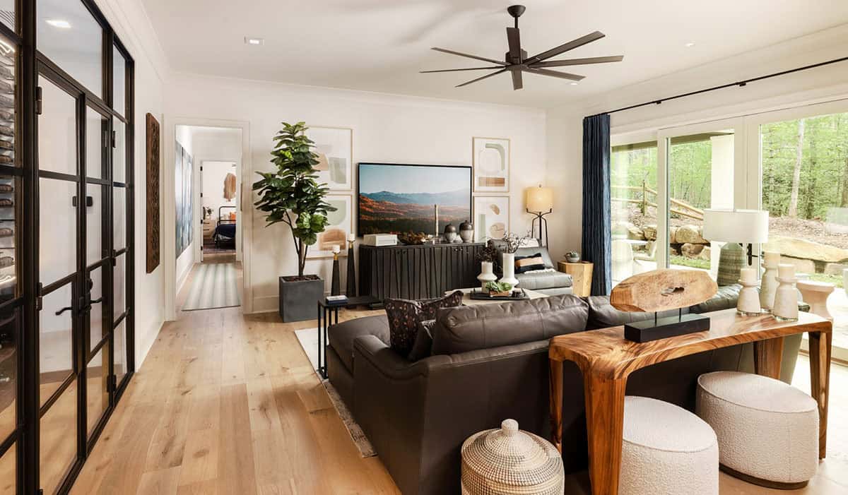 Basement rec room with dark leather sofa, live-edge console, and glass wine cellar doors