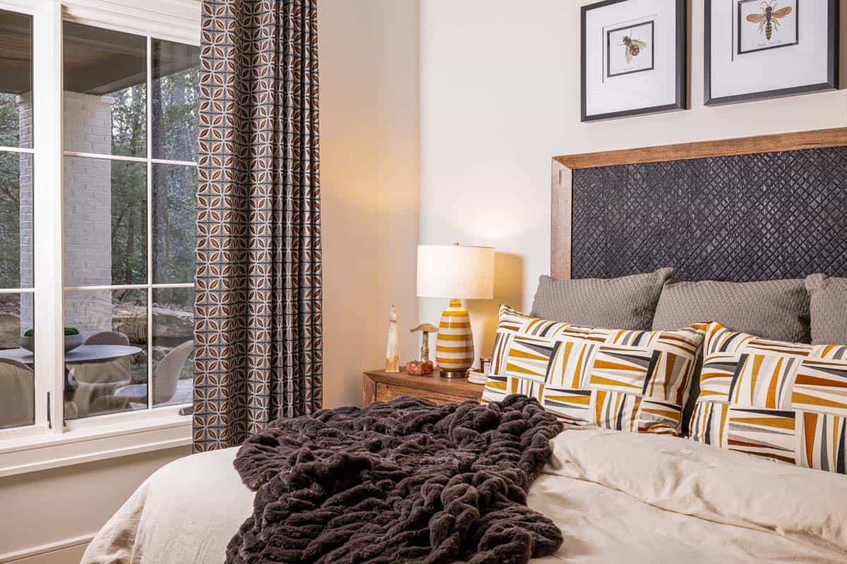 Guest bedroom with dark quilted headboard, graphic stripe pillows, and insect botanical prints