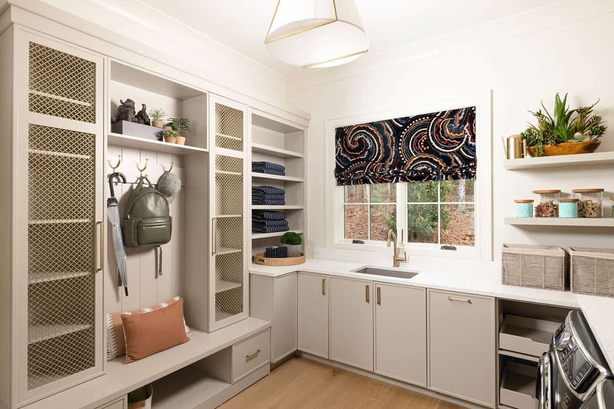 Mudroom and laundry room with taupe built-ins, mesh cabinet doors, and bold roman shade