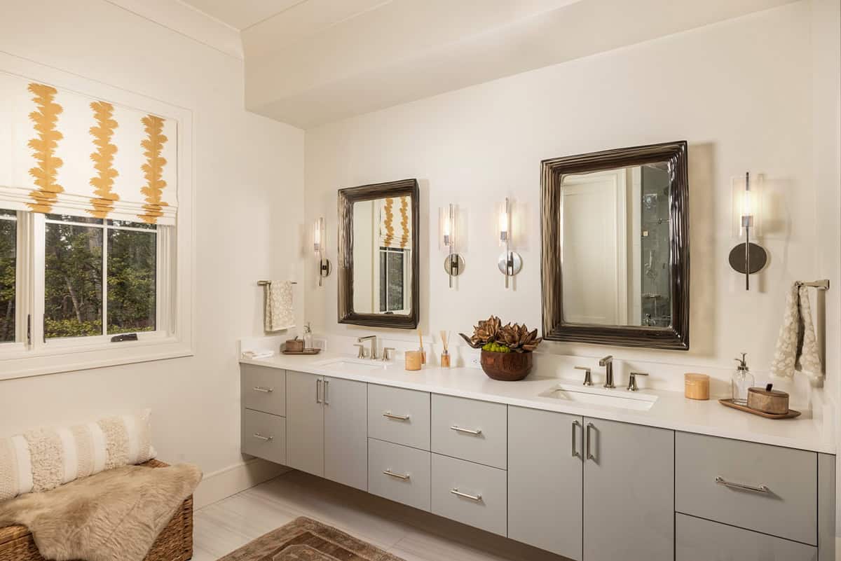 Primary bathroom double vanity with floating gray cabinets and paired dark-framed mirrors