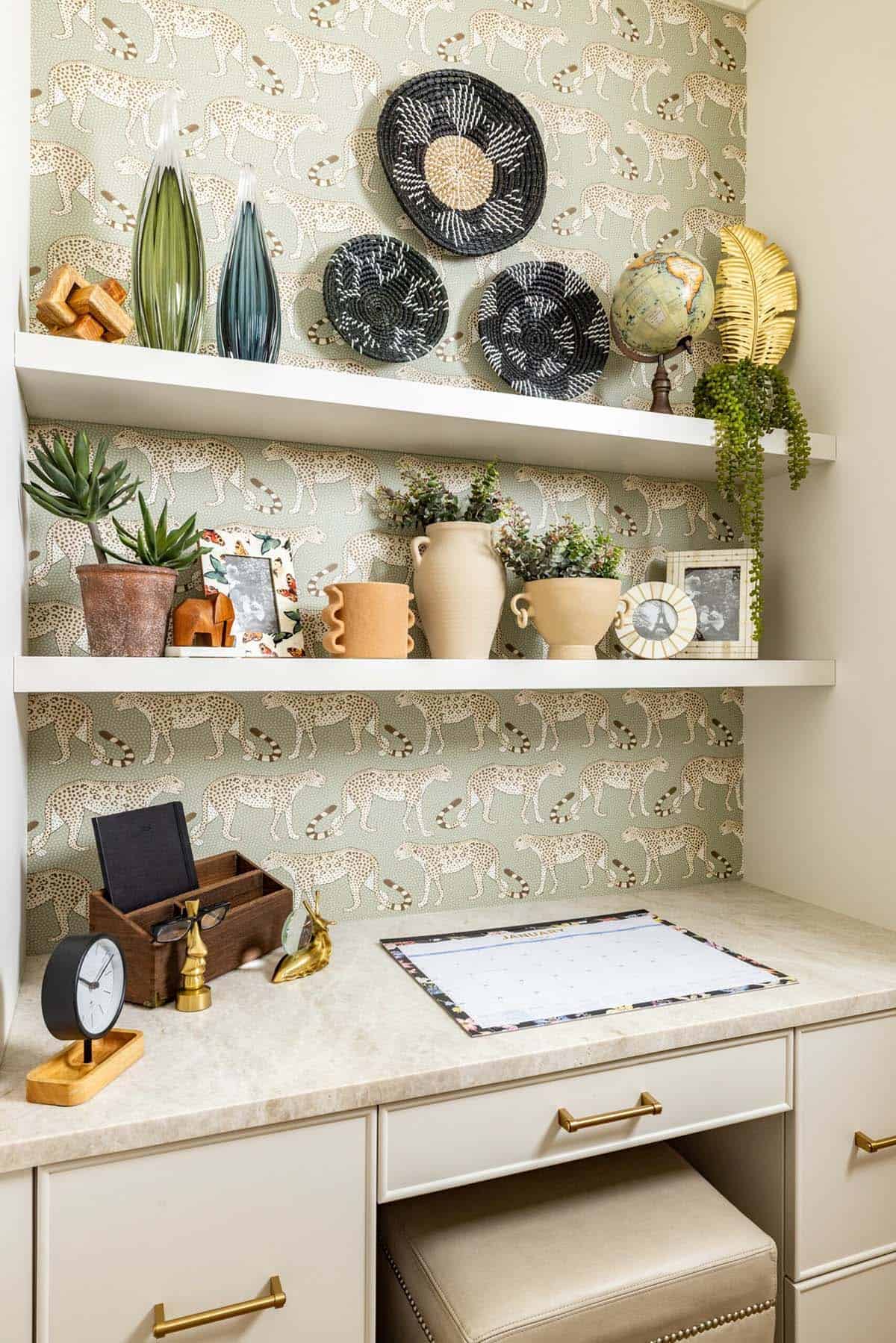 Built-in home office desk nook with cheetah print wallpaper and styled open shelving