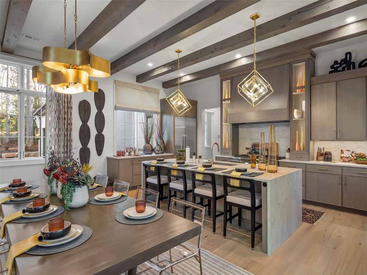 Kitchen and dining area with gray-taupe cabinets, gold cube pendant lights, large island, and decorative ceiling beams
