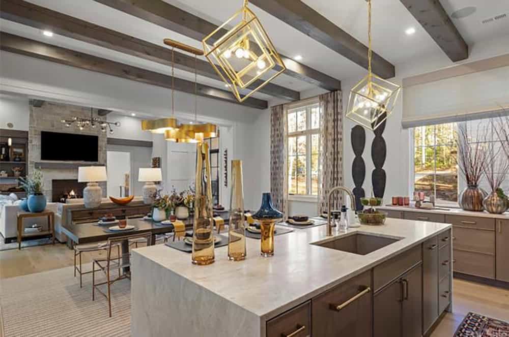 Kitchen island with stone countertop overlooking open-plan dining and living areas with stone fireplace