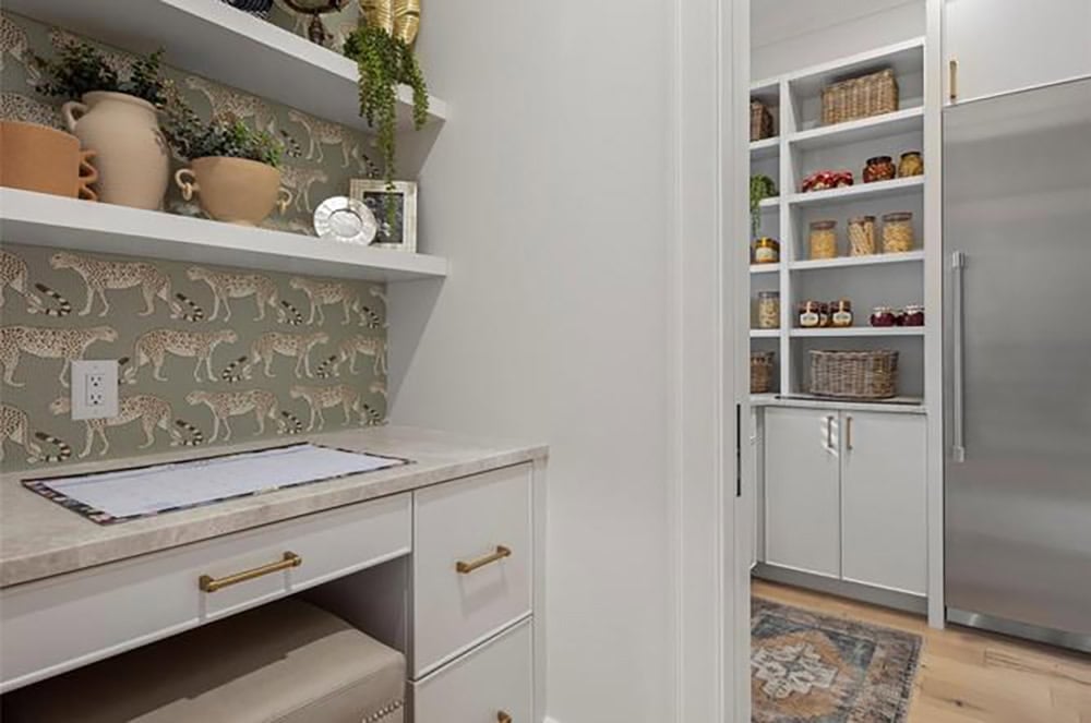 Butler's pantry with leopard-print wallpaper backsplash, marble counters, and walk-in pantry with built-in shelving