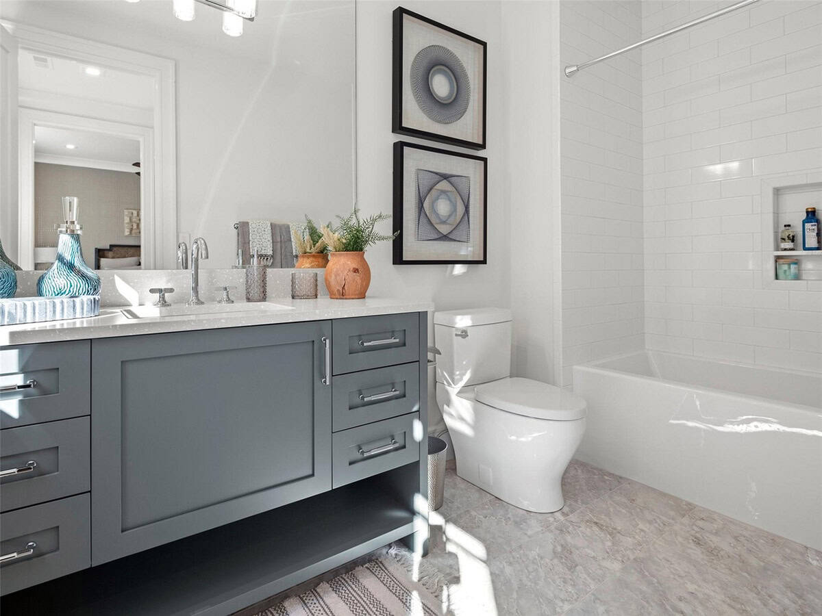 Guest bathroom with gray shaker vanity, white quartz countertop, subway tile tub surround, and geometric wall art