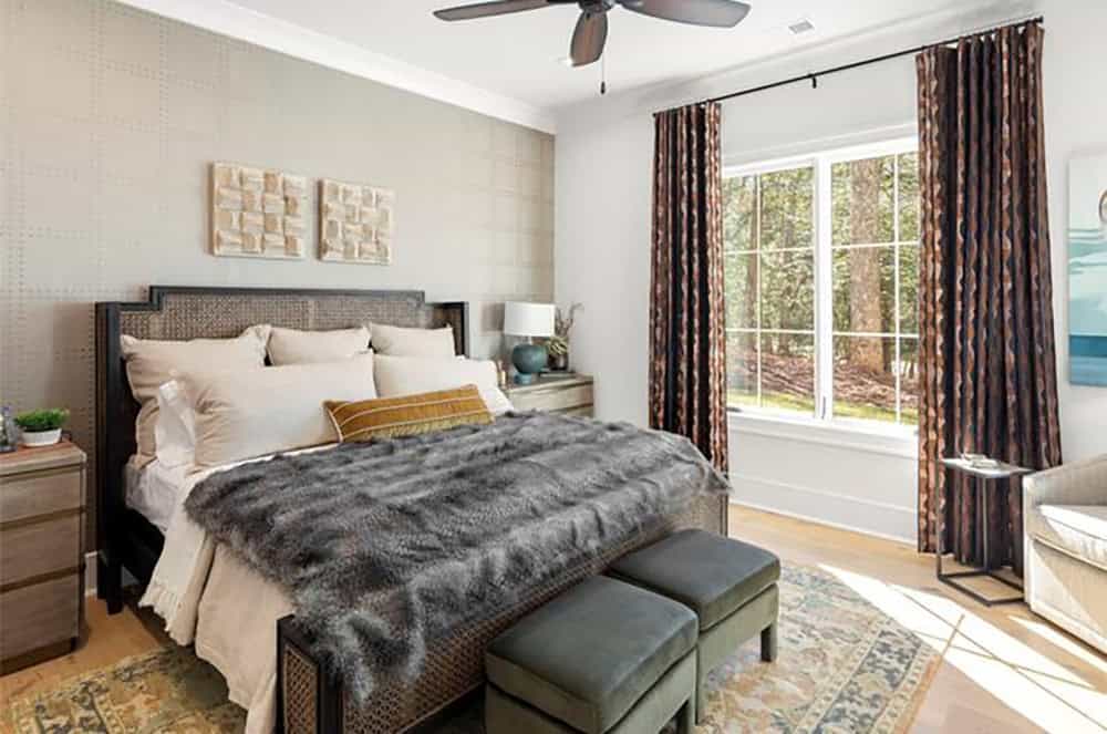 Guest bedroom with cane-panel headboard, faux fur throw, textured wallpaper accent wall, and patterned drapes