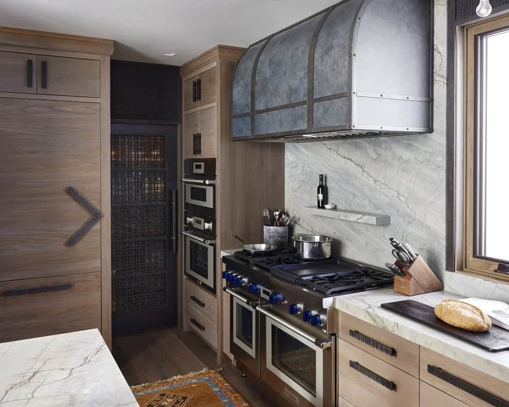 Kitchen cooking area with professional range, arched metal hood, marble backsplash, and wood cabinetry