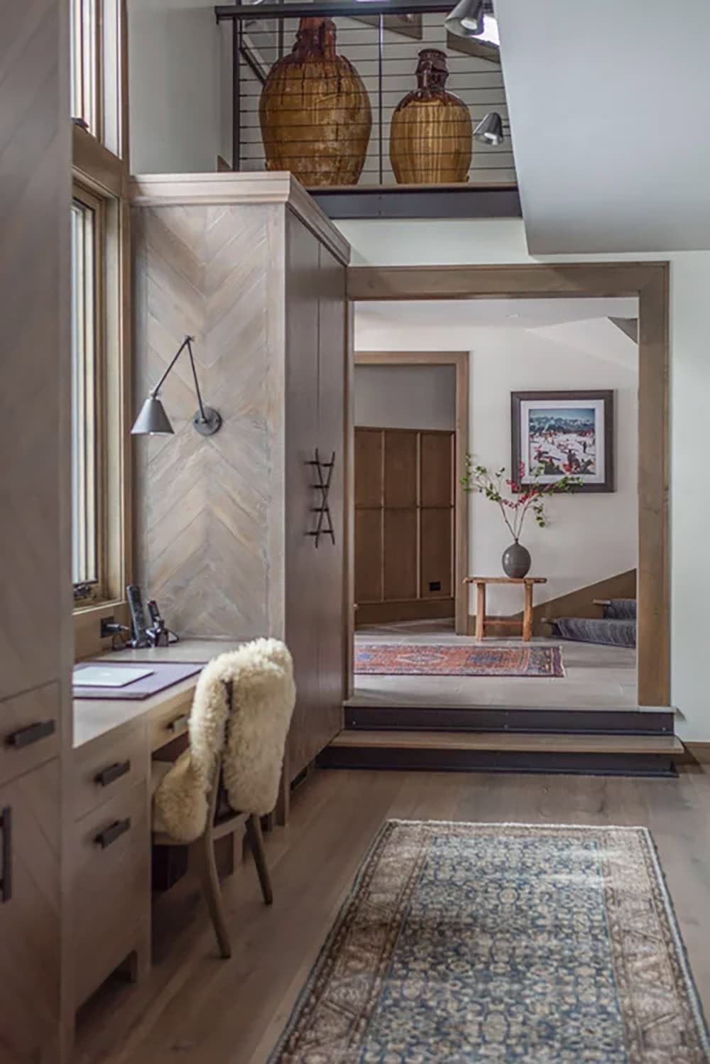 Built-in desk nook with herringbone wood paneling, swing-arm lamp, and hallway leading to entry foyer