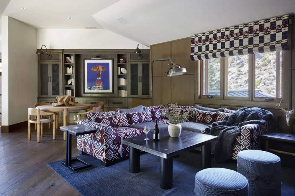 Lower-level lounge with bold ikat sectional, built-in shelving, dark coffee table, and river canyon views