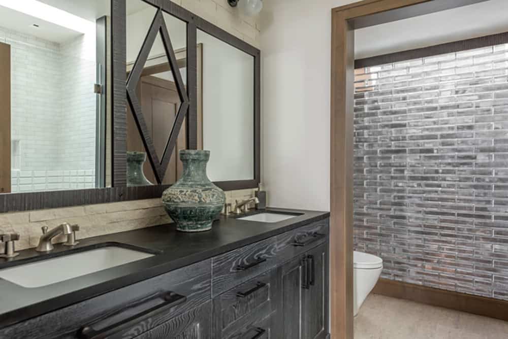 Guest bathroom with dark wood double vanity, geometric mirror, and mosaic tile accent wall