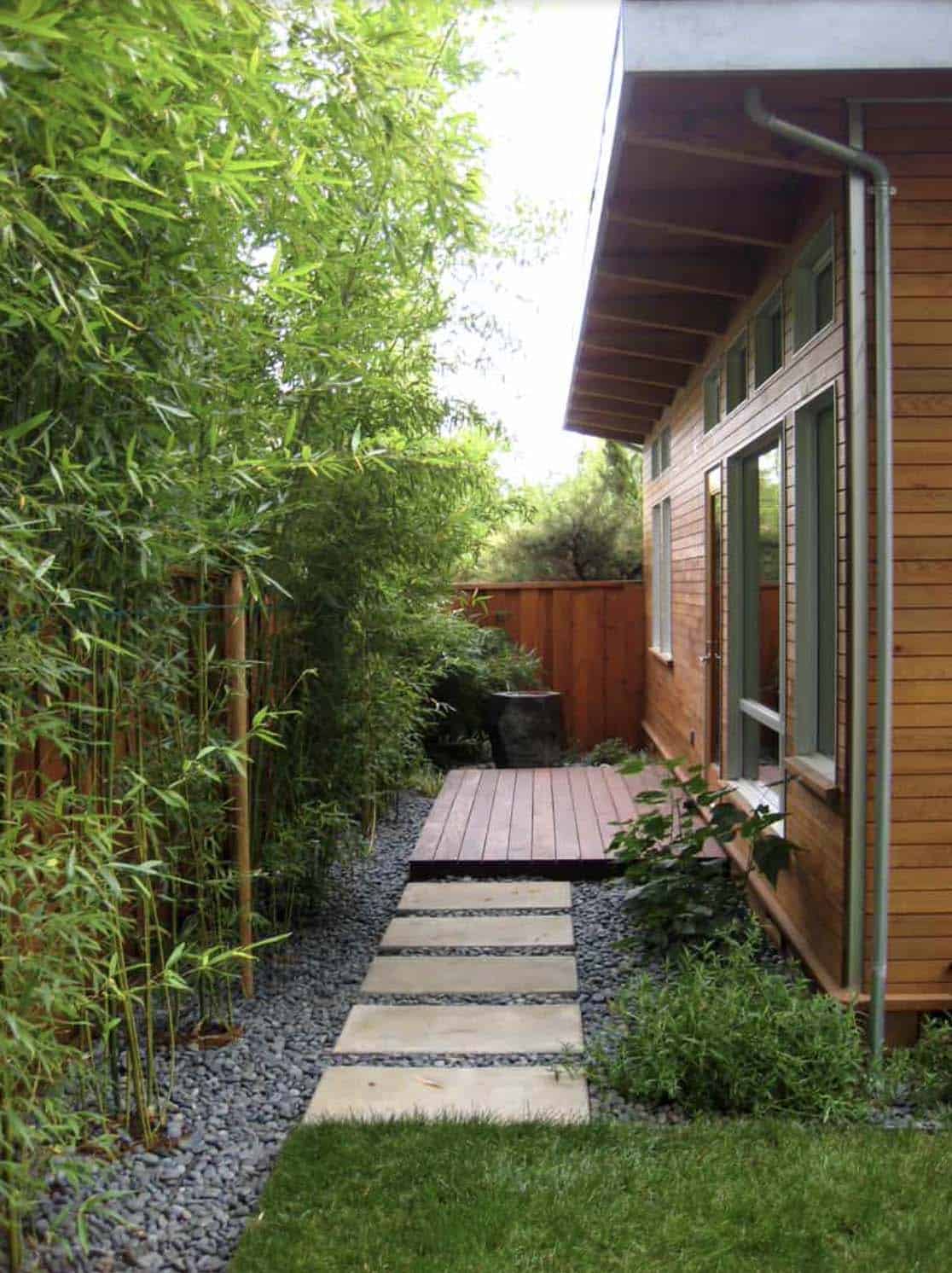 Tall bamboo privacy screen alongside a side yard path with stepping stones and gravel