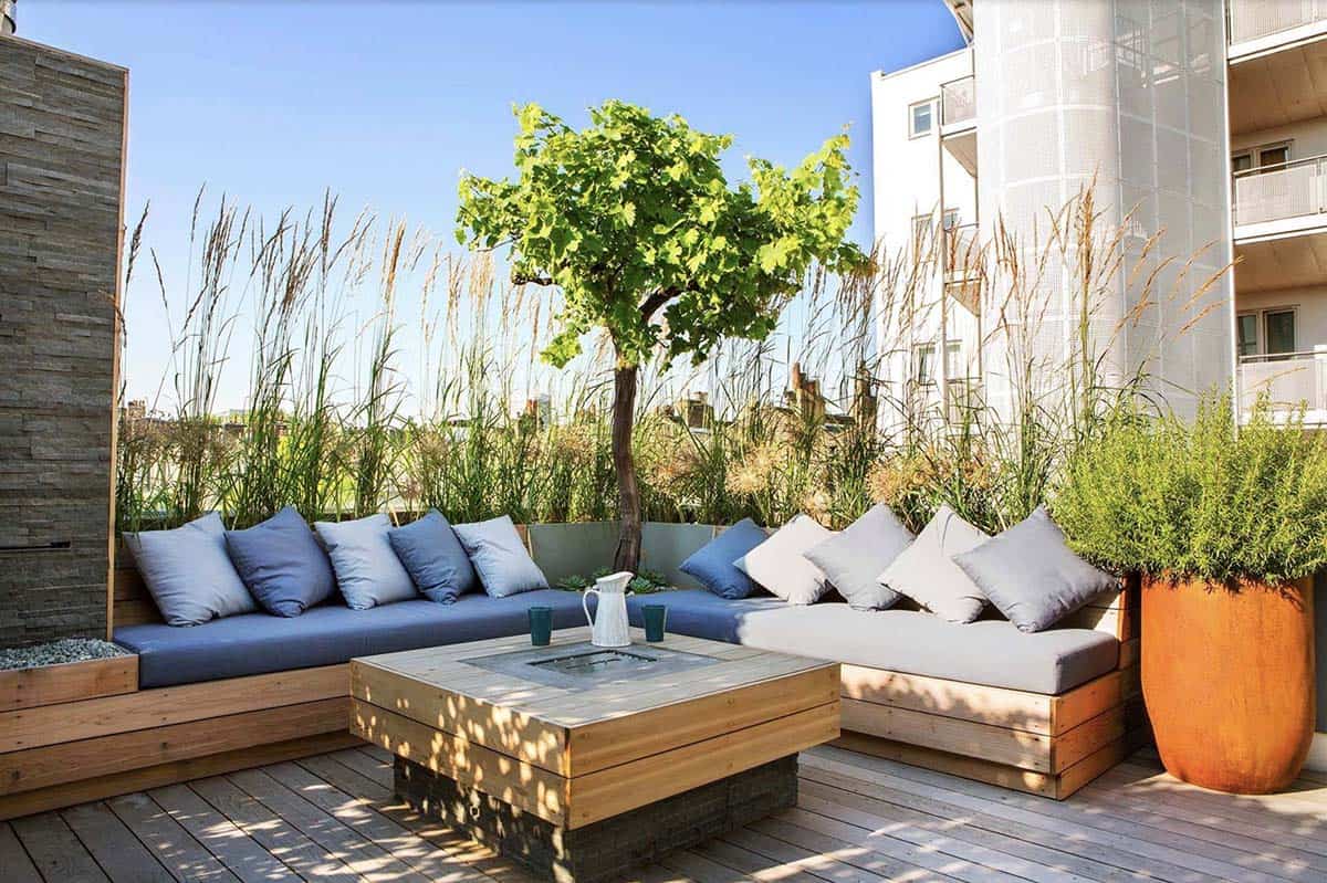 Rooftop deck with built-in wooden bench seating, tall ornamental grasses, and a small tree