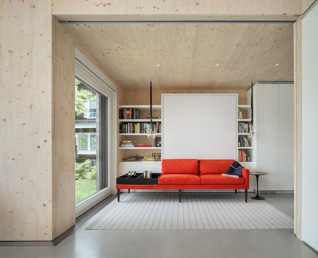 CLT bedroom with Murphy bed folded up, revealing red sofa and built-in bookshelves
