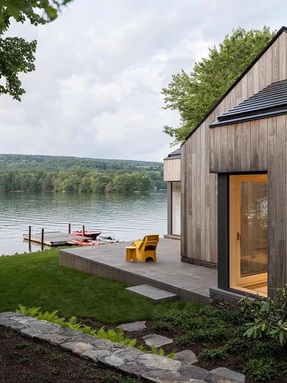 Lakeside terrace of CLT house in Connecticut with yellow chair, stone wall, and private dock