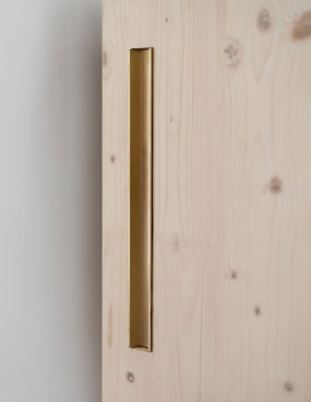 Recessed brass pull handle detail on a cross-laminated timber sliding door