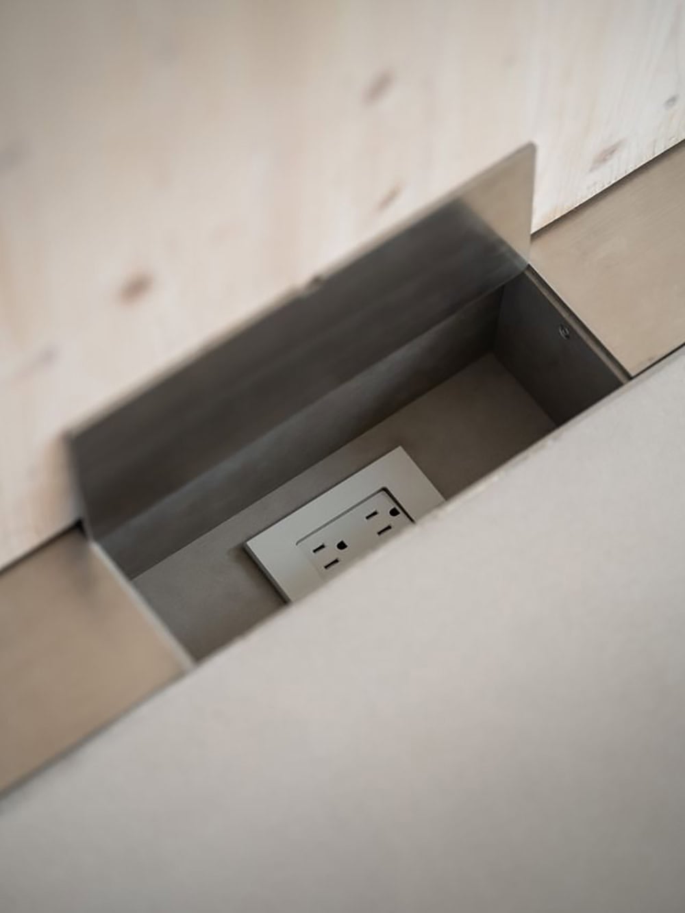 Hidden electrical outlet recessed into a metal box flush with a CLT countertop
