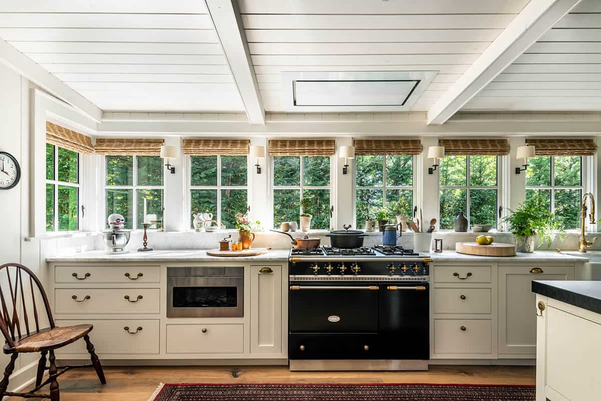 Bright kitchen with black Lacanche range, cream cabinets, and garden-view windows