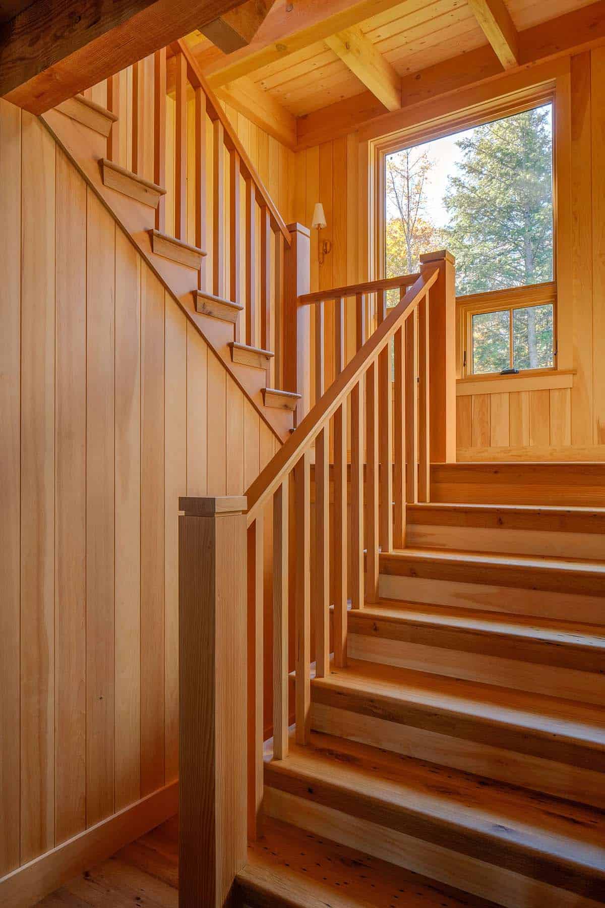 Handcrafted wood staircase with vertical-slat railing, knotty pine walls, and tall landing window