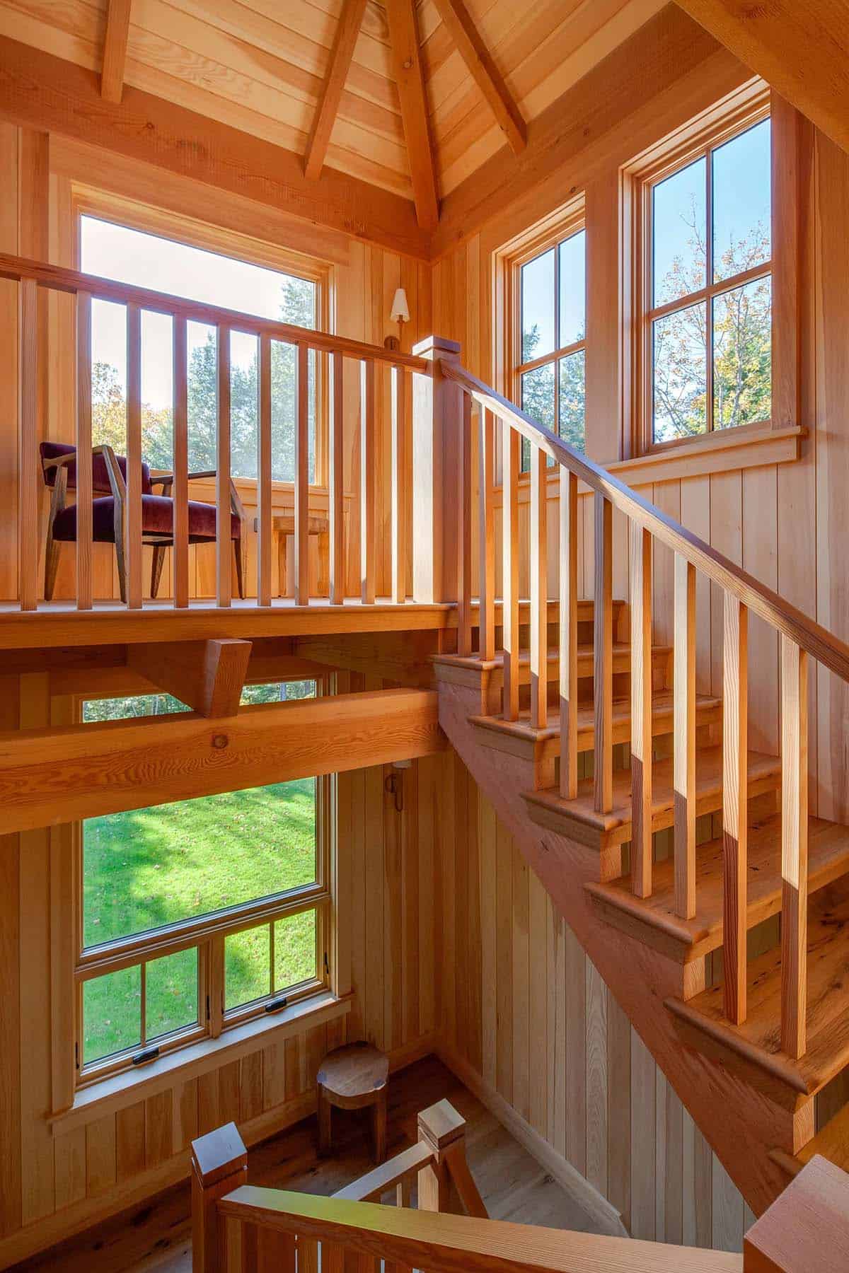 Multi-story stair tower with timber framing, vertical wood balusters, and wraparound windows flooding light 