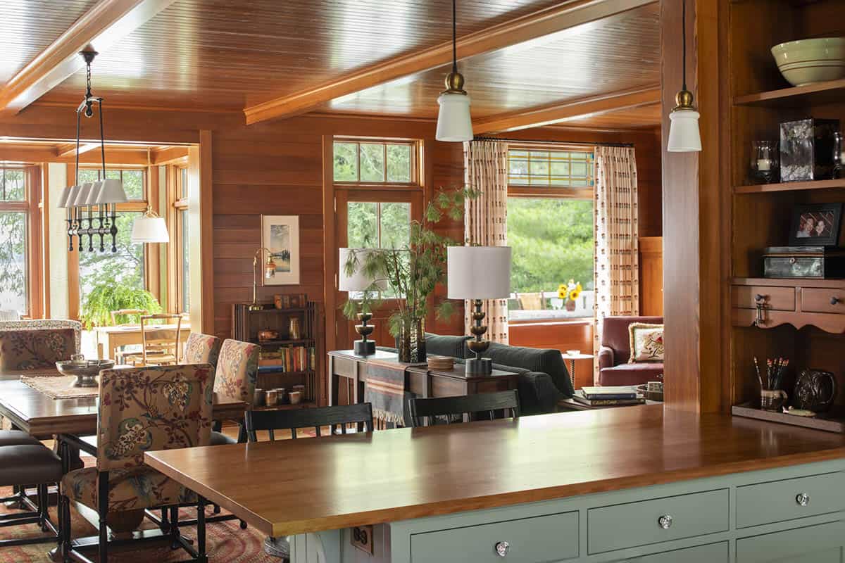 Kitchen and great room viewed from the island, showing wood-paneled walls and abundant natural light