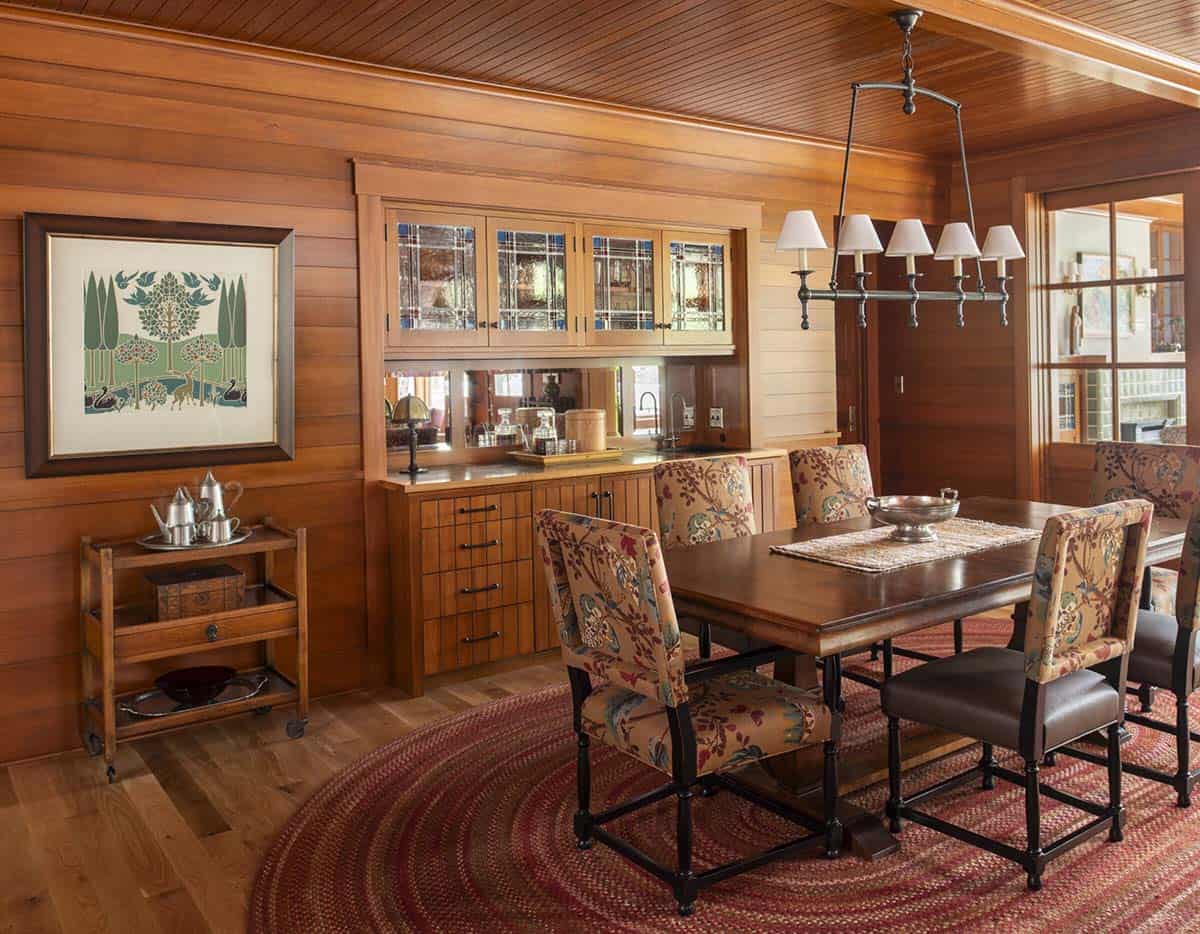 Dining room with wood-paneled walls, floral upholstered chairs, built-in buffet, and Arts and Crafts chandelier