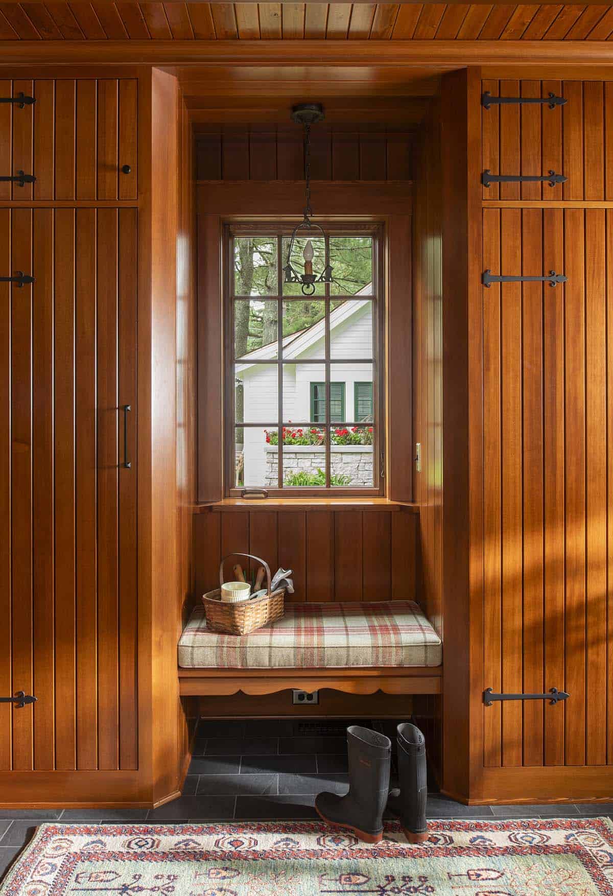 Mudroom with cedar-paneled storage cabinets, built-in bench with plaid cushion, and rain boots
