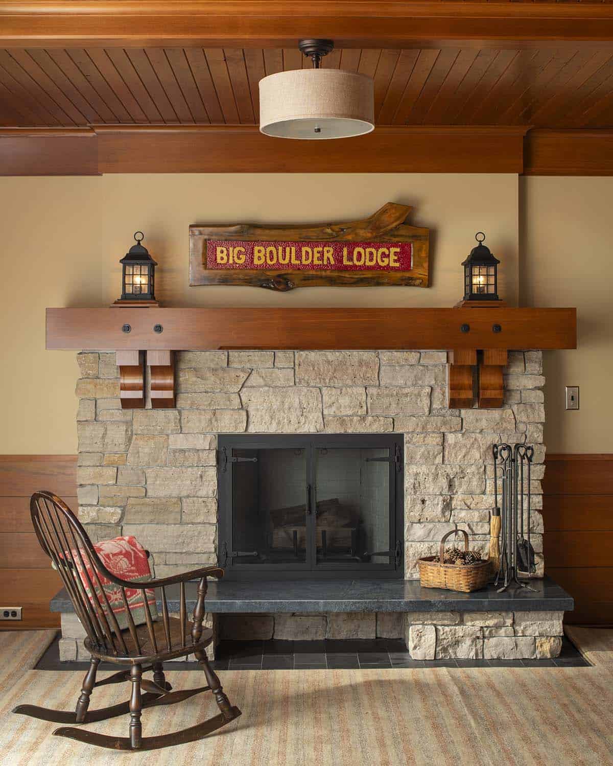 Stone fireplace with wood mantel and Big Boulder Lodge hooked-rug sign