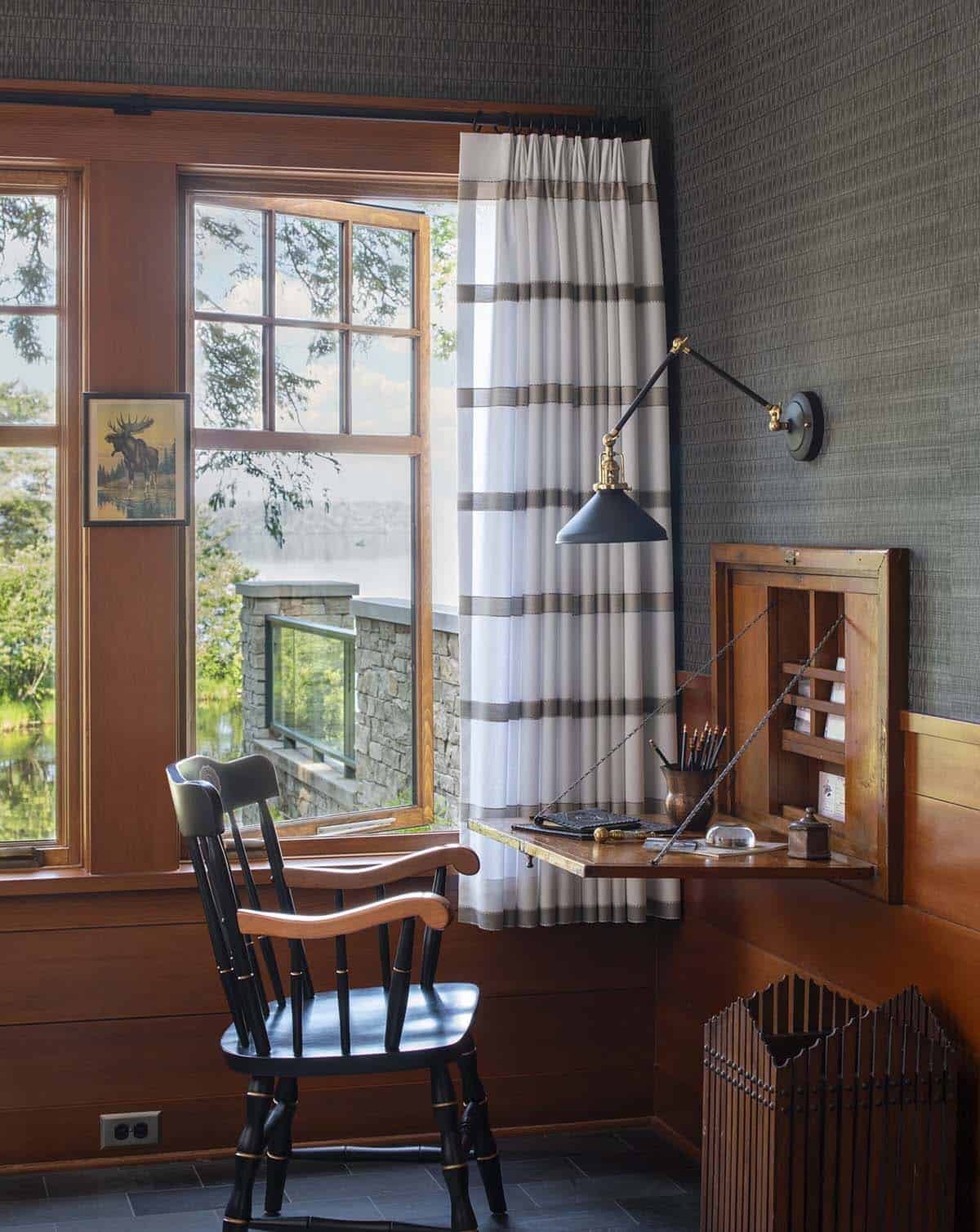 Corner bedroom workspace with fold-down desk, swing-arm lamp, and lake view through gridded window