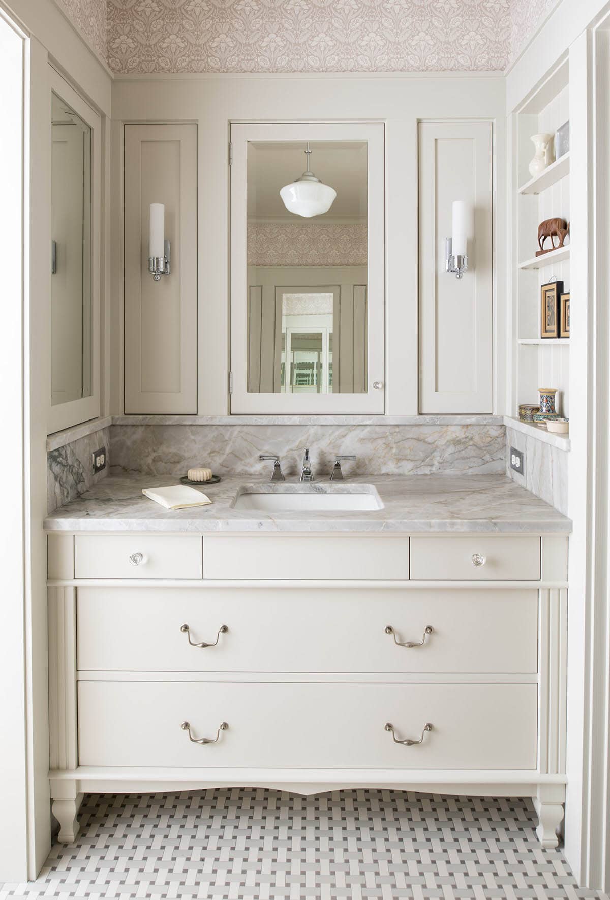Elegant white bathroom vanity with marble countertop, basket-weave tile floor, and damask wallpapered ceiling