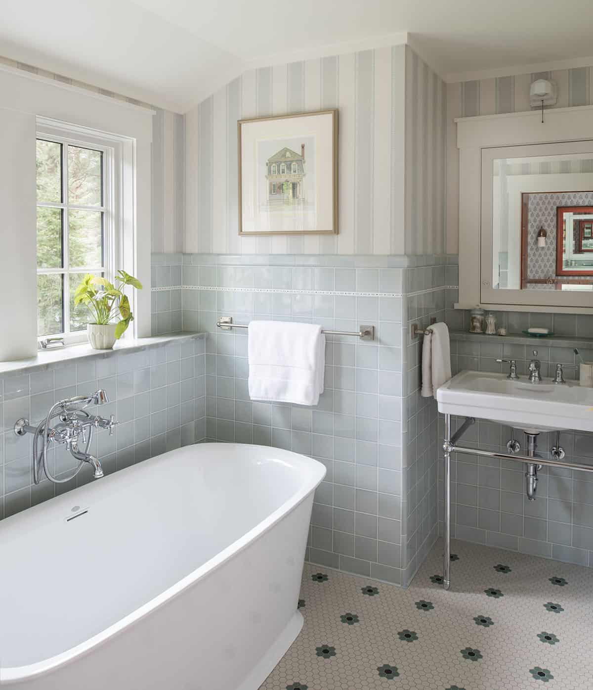 Classic bathroom with freestanding soaking tub, pale blue subway tile, striped wallpaper, and pedestal sink