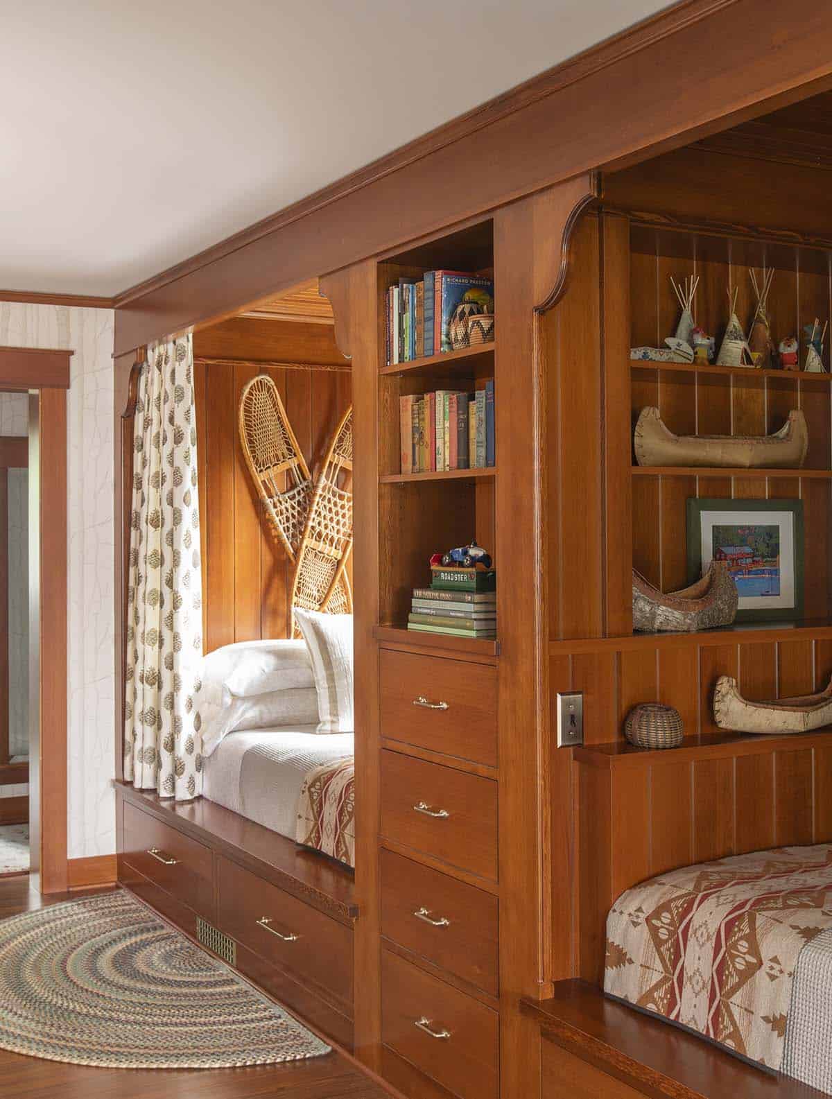 Children's bunk room with built-in cedar beds, curtained sleeping nooks, and camp-themed shelving