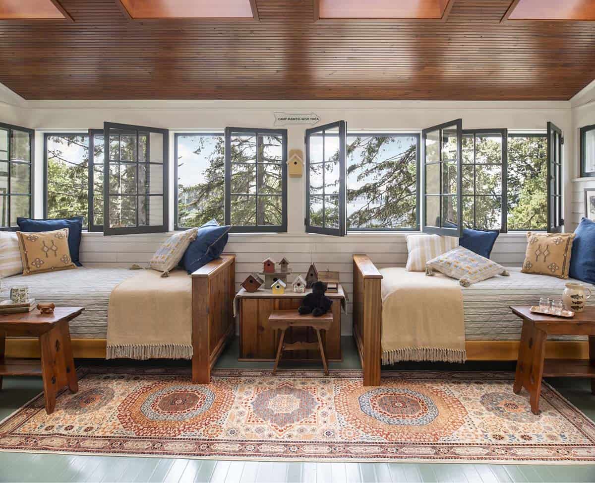 Children's bunk room with built-in cedar beds, curtained sleeping nooks, and camp-themed shelving