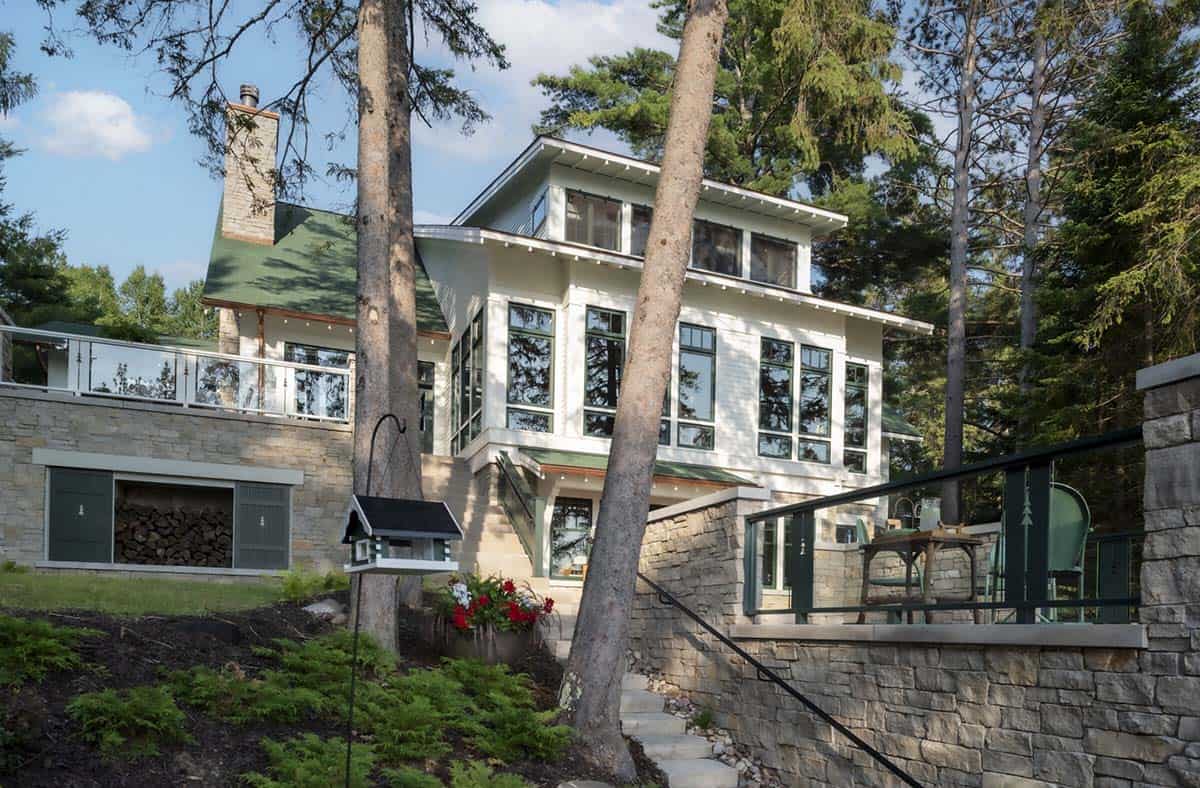 Lake-facing exterior of the cabin showing stone terraces, glass railings, and large windows